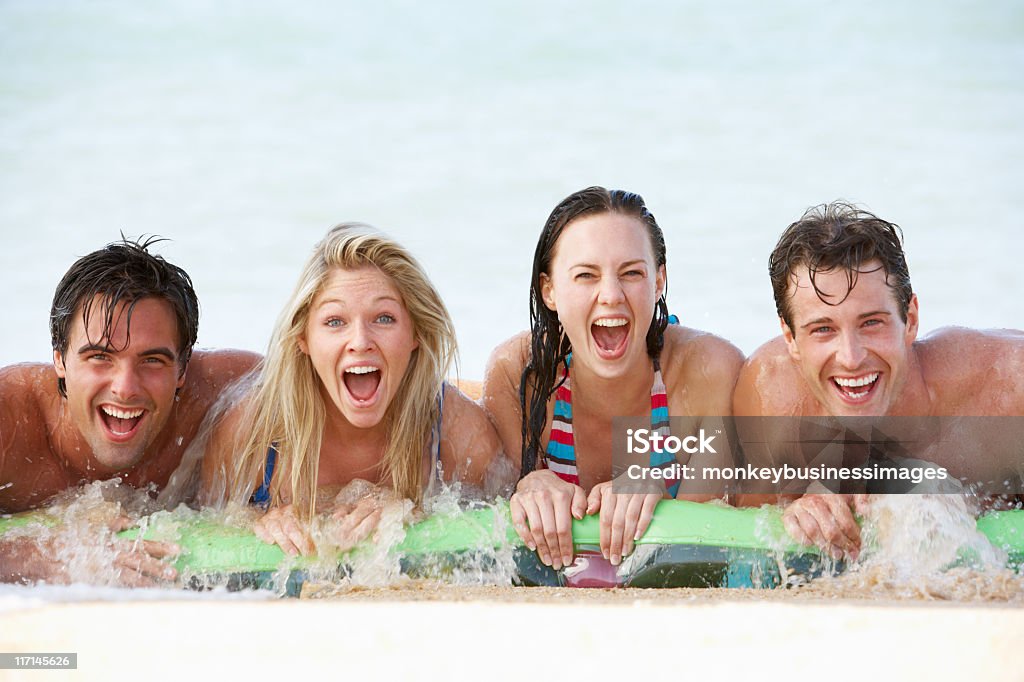 Gruppo di amici che si diverte nel mare su Airbed - Foto stock royalty-free di Adulto