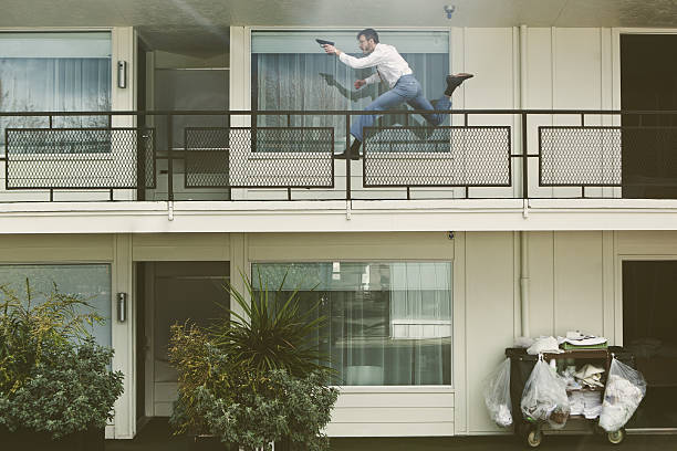 A two dimensional view of a spy or undercover agent running down a vintage California style hotel balcony of a dark hotel, gun in hand.  Big chops sideburns, classy mustache, and glasses. Horizontal with copy space; LOW CONTRAST intentional to emulate a 1970's style film look.