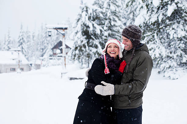 Beautiful Young Couple Embracing in Winter Snow, Copy Space Happy young couple having fun outside a snowy lodge. ski lift photos stock pictures, royalty-free photos & images