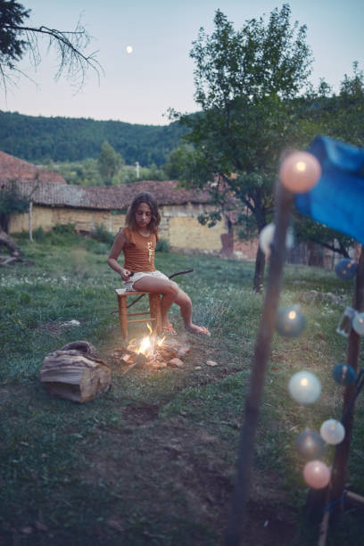 istock Small child girl making campfire on a lawn. 1171457383