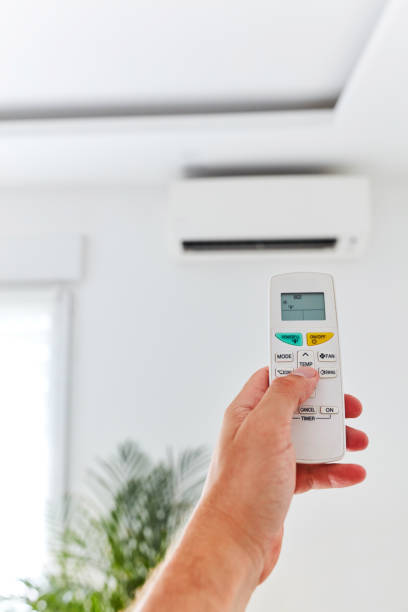 istock Modern air-conditioned unit with a hand holding a remote. 1171457564