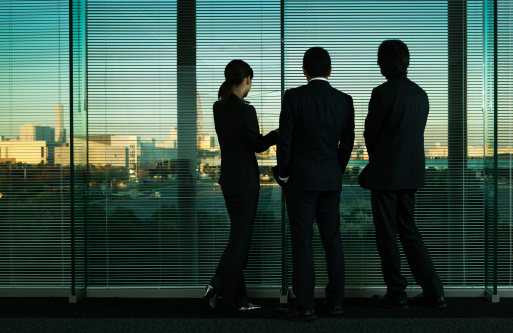 Subject: A group of Asian business office workers looking out the window at the city skyline.