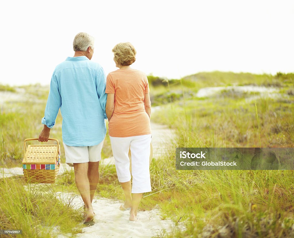 Out for a picnic Retired couple walking with picnic basket 50-59 Years Stock Photo