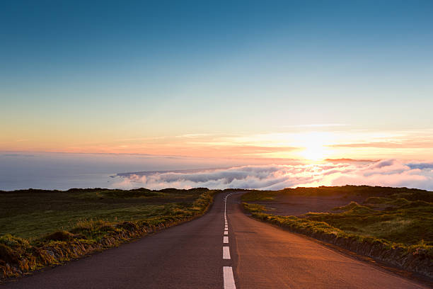 Sunset Highway into the Clouds Highway through the beautiful nature down towards the atlantic ocean, leading into amazing cloudscape and sunset. country road photos stock pictures, royalty-free photos & images