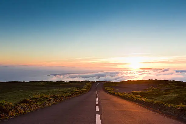 Highway through the beautiful nature down towards the atlantic ocean, leading into amazing cloudscape and sunset.