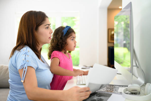 Hispanic mother and daughter working at home on computer