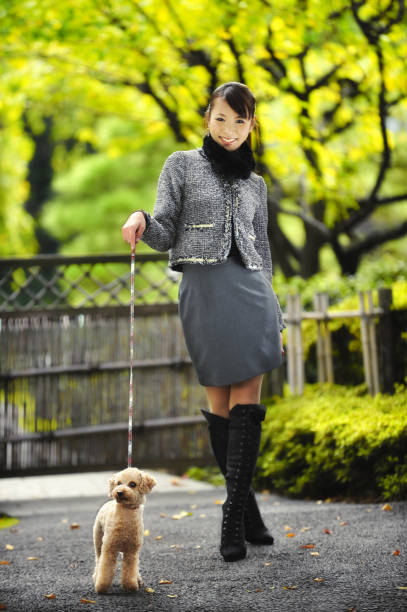 A woman carrying her adopted stray dog in her arms during autumn.