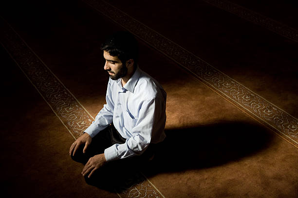 praying Muslims during prayer in a mosque in Samarkand, Uzbekistan. Muslim men during evening prayer inside the mosque.