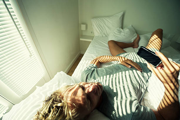 istock Man Relaxing in Bed with Smartphone Wearing Underwear 117146235