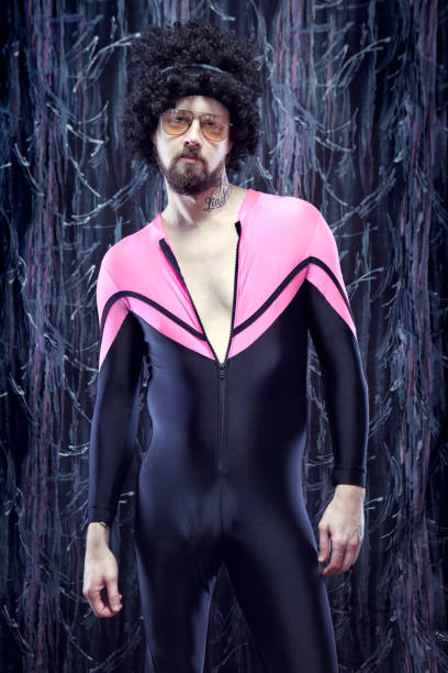 Afro Aerobics Instructor from the 1980's A "Richard Simmons"-like man with big curly hair and a skin tight black and pink body suit unitard poses with a macho look in his retro pastel 80's style aerobics studio. 80s aerobics stock pictures, royalty-free photos & images