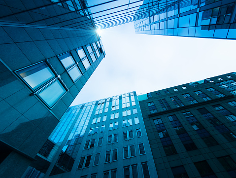 Wide angle image depicting an abstract view looking up at various different modern buildings and futuristic skyscrapers in central London, UK. It is an urban jungle comprised of glass and steel, leading lines and abstract geometric shapes.