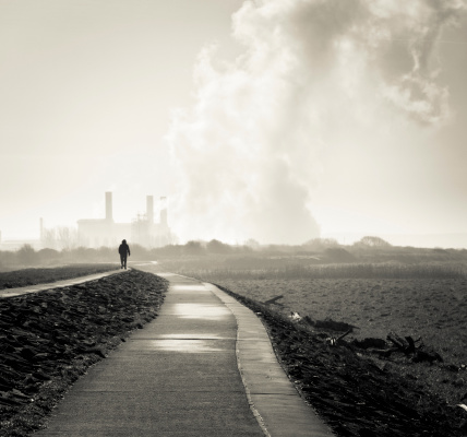 Woman walking to the factory. black and white picture with yellow toning. shallow depth of field.