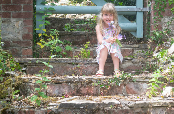 A child sits on steps by a gate