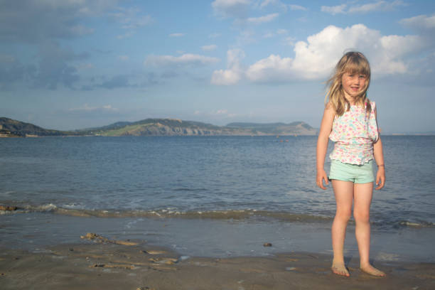 A 6 year old girl looks at the camera by the seaside.