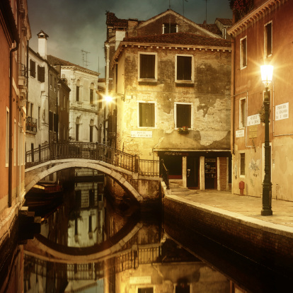 Typical cityscape view of Venice. Narrow canal with emerald water between ancient red brick buildings. Famous touristic place and travel destination in Europe. Winter drizzle day in Venice.