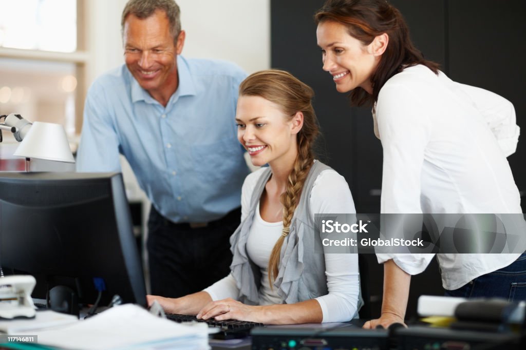 Happy business employees looking at computer monitor Happy business employees looking at computer monitor in the office 20-29 Years Stock Photo
