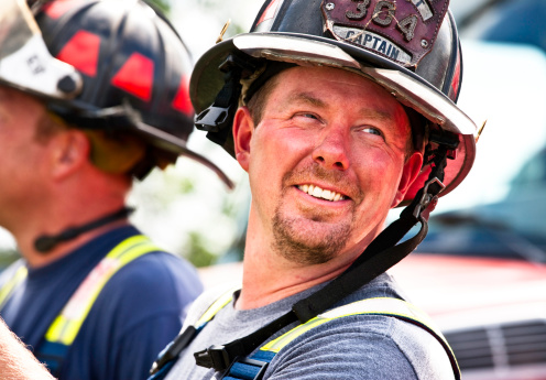 A rugged 41 year old volunteer firefighter takes a break while battling a house fire.