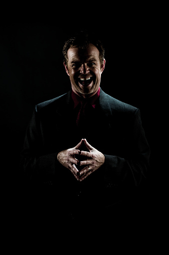 Man on black background with crazy look and mouth open laughing.