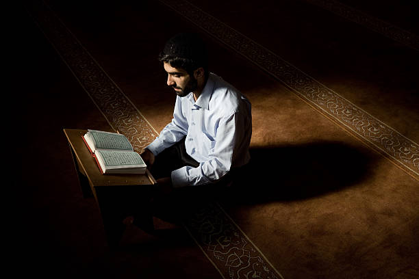 Young muslim man reading Koran in mosque