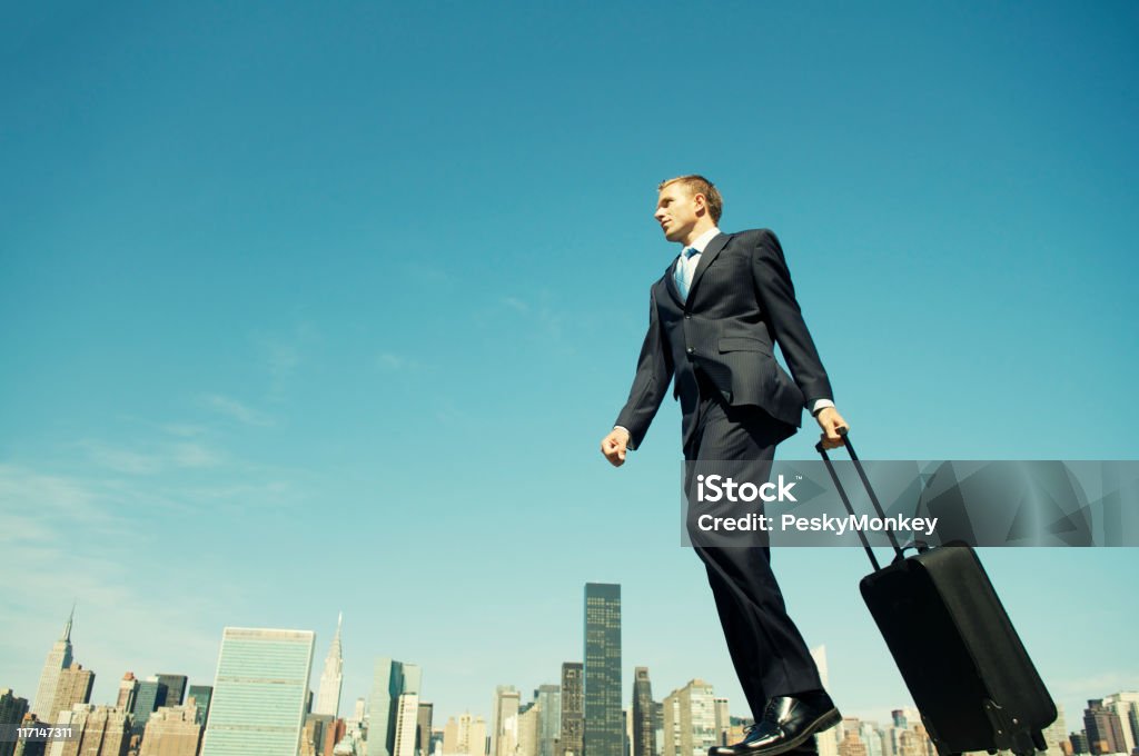 Uomo d'affari in viaggio valigia su Skyline Wheeling - Foto stock royalty-free di Camminare