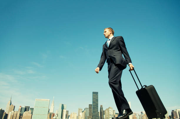 istock Traveling Businessman Wheeling Suitcase Across Skyline 117147311
