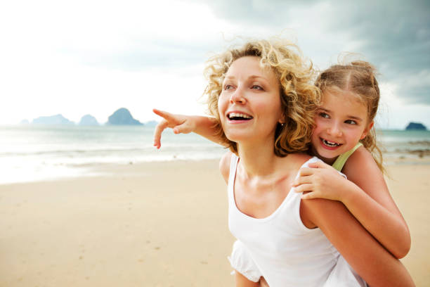 mère et fille s'amuser sur la plage - mother holding child pointing photos et images de collection