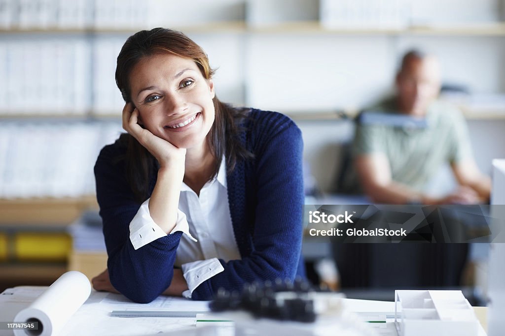 Relaxed architect at work with male colleague in the background Relaxed female architect at work with male colleague in the background 30-39 Years Stock Photo