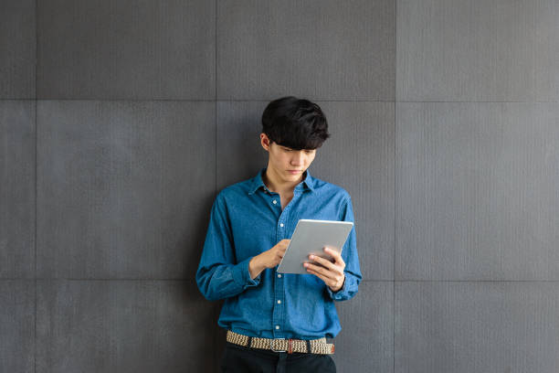 istock Portrait of young Asian Business man using digital tablet computer on gray background 1171475624