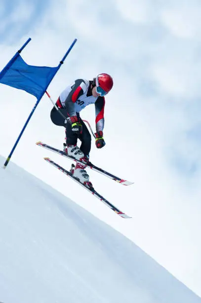 Side view of young male skier at straight downhill race in mid-air