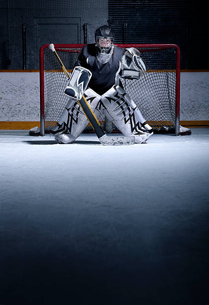 Youth Hockey Goalie A young, female, hockey goalie in position on the ice. There is ample copy space. ice hockey net stock pictures, royalty-free photos & images