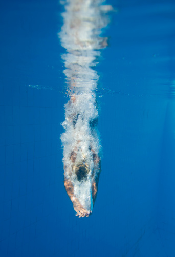 Female diver enters the water of a swimming pool