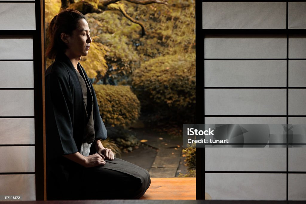 Japanese Man Young man sitting in front of his house. Japanese Garden Stock Photo