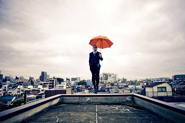 empresário japonês com guarda-chuva flutuante acima de tóquio - men businessman jumping levitation imagens e fotografias de stock