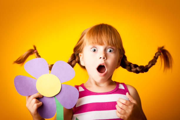 istock Surprised, Red-Haired Girl with Upward Braids and Oversized Flower 117148434