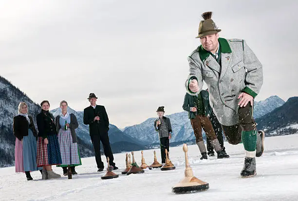 Austrians in traditional Tracht curling on the frozen Lake Grundlsee in front of a stunning Alps Panorama. Great Dynamic in play action. You can even see the snow spraying from the player in Lederhosen. Nikon D3X. Converted from RAW.