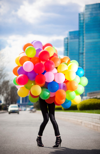 Young woman posing with 150 helium colorful balloons