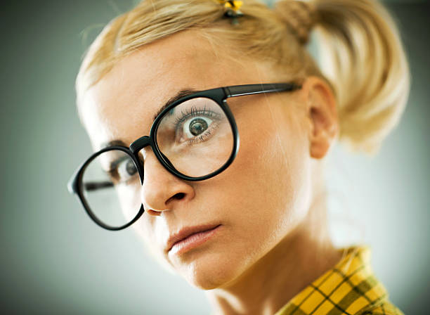 half portrait of a young blonde woman with glasses looking up on a white studio background