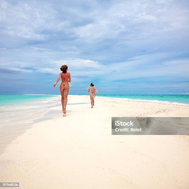 Photo libre de droit de Mère Avec Sa Fille En Bikini Course Sur Plage Tropicale banque d'images et plus d'images libres de droit de Famille