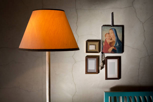 Room of an old house with yellow lamp. Hung on the wall is an old painting on wood of a Madonna with Child.