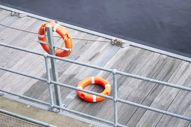 Lifebuoy orange ring on sea pontoon for water safety at marina uk