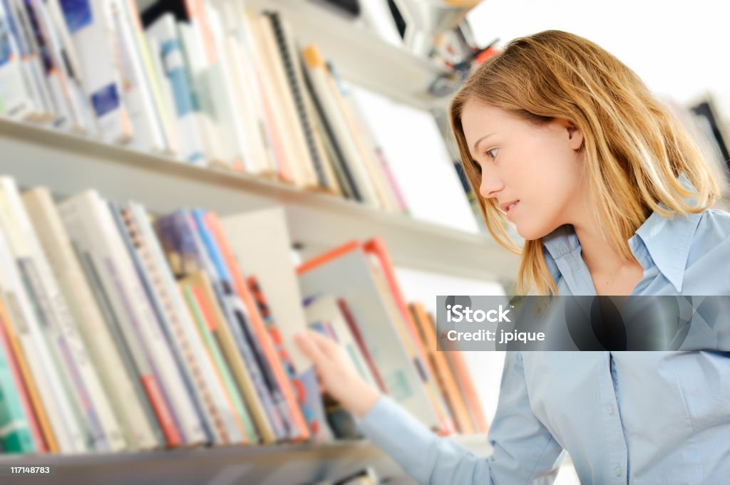 Подросток поиск книги в библиотеке - Стоковые фото Библиотека роялти-фри