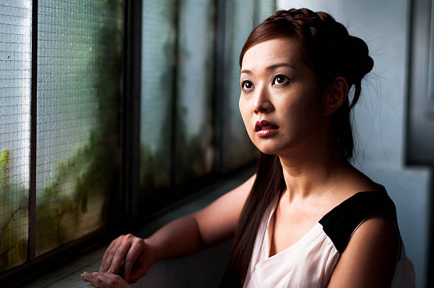 istock A concerned girl looking up sitting at a table by a window. 117148825