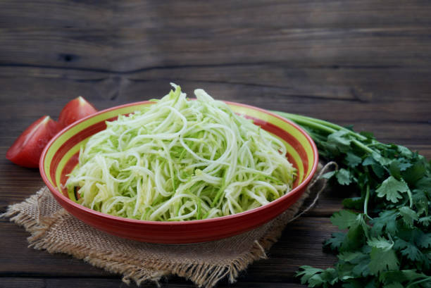 istock Cut the zucchini into fine long shreds isolated on wood background 1171489721