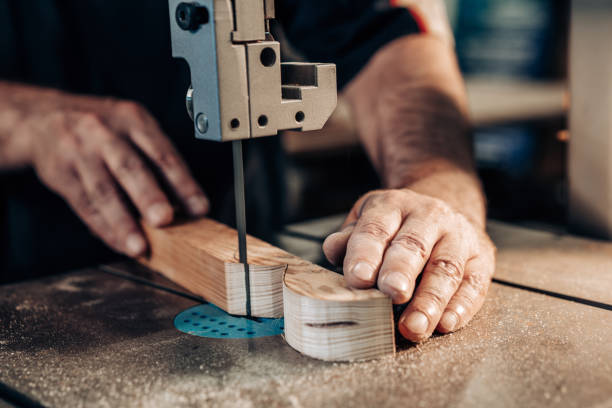 istock Carpenter working in workshop. Joiner labourer cuts wooden plank on jigsaw machine. Handwork, carpentry concept, woodworking. 1171490842