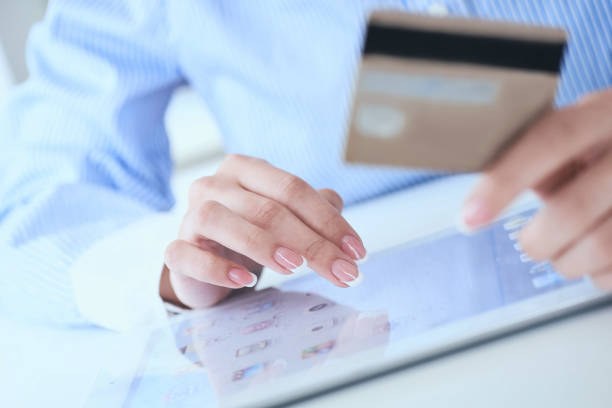istock Close-up woman's hands holding a credit card and using tablet pc for online shopping. Middle section of young businesswoman making online payments with credit card and tablet. 1171490984