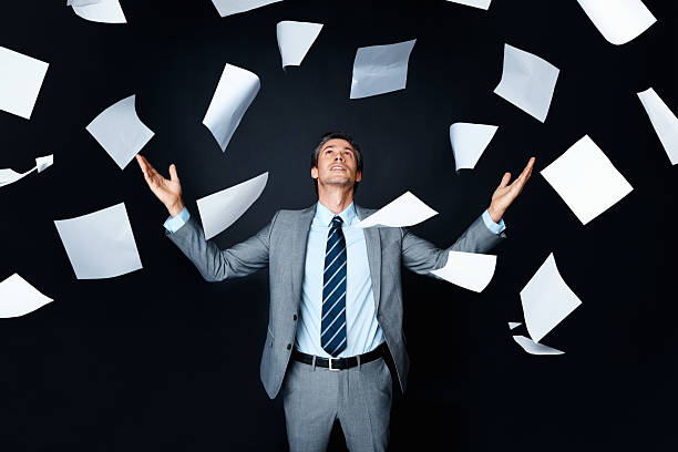istock Man wearing suit looking up at papers in the air 117149431