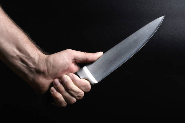 istock a big shiny knife in hand on a black background 1171494975