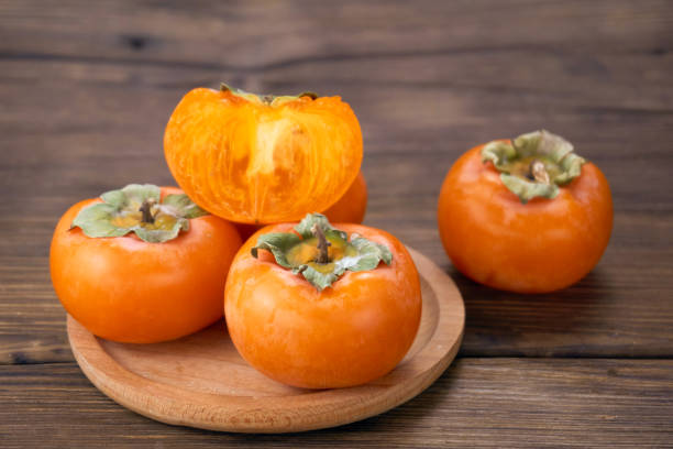 istock fresh ripe persimmons isolated on wood background 1171495464