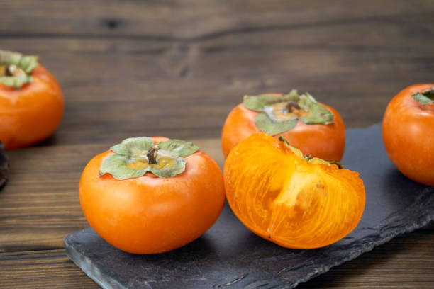 istock fresh ripe persimmons isolated on wood background 1171495522