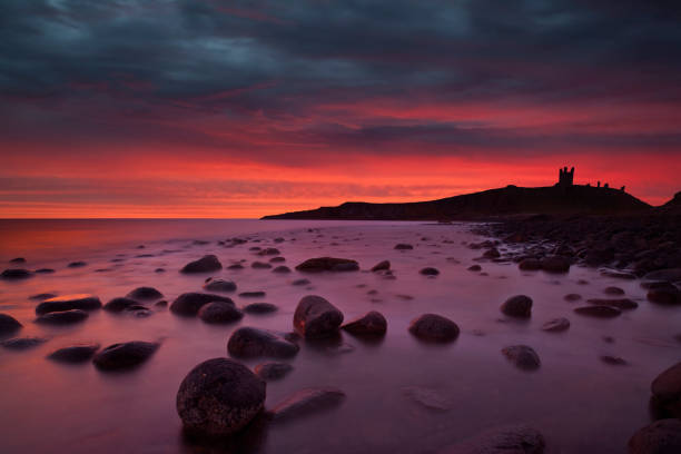 castello di dunstanburgh all'alba. - bamburgh northumberland england beach cloud foto e immagini stock